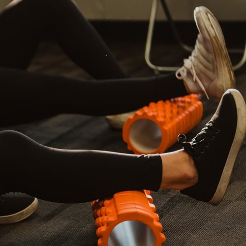 Patient performing a leg rehabilitation exercise with a foam roller during a physiotherapy session