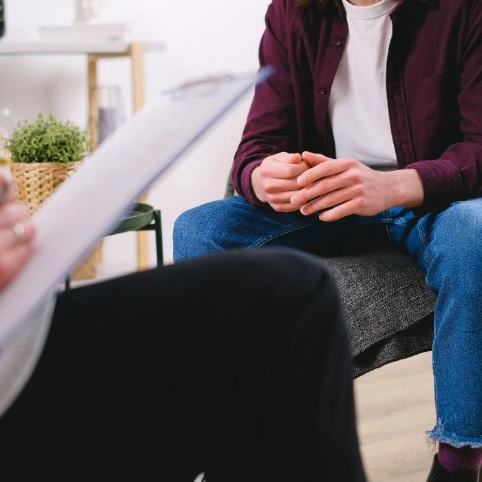 Patient sitting with counselor during therapy session, discussing personal challenges in a calm and supportive environment